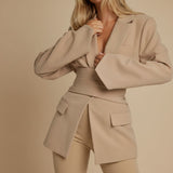 Yemelia beige tailored blazer with relaxed fit, featuring a self-tie belt, lapel neckline, and front pockets. Made from smooth, structured fabric.