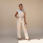 Yemelia beige flutter sleeve wide leg jumpsuit with adjustable waist tie and full-length silhouette.