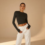 Yemelia black long sleeve fitted top with thumbhole detail and minimalist neckline, made from stretch fabric.