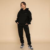 Yemelia black relaxed fit hoodie and jogger set with subtle graphic accent. Soft fabric, elastic waistband, ideal for casual wear.