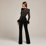 Yemelia black lace jumpsuit with feather cuffs, structured shoulders, and flared legs. Elegant evening wear.