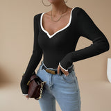 Yemelia black ribbed long sleeve top with white contrast trim V-neck and cuffs, fitted silhouette.