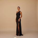 Yemelia black satin sleeveless evening gown with high slit and refined neckline. Floor-length, figure-flattering.
