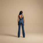 Yemelia blue denim jumpsuit with deep V halter neckline and heart-shaped back cutout, flared legs.