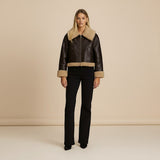 Yemelia brown faux leather jacket with shearling trim on collar, cuffs, and hem. Zip front closure.