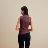 Yemelia sleeveless draped faux leather top in deep burgundy with a high neckline and asymmetric hem.