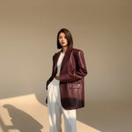 Yemelia oversized burgundy faux leather blazer with tailored structure, classic lapels, and functional pockets.