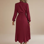 Yemelia burgundy long sleeve pleated midi dress with high neck and waist tie. Elegant, flowing silhouette.