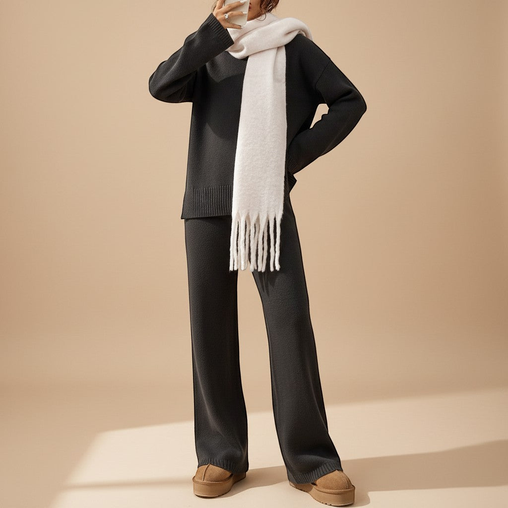 Yemelia charcoal knit lounge set with relaxed sweater and wide leg pants, featuring ribbed details and a cream fringed scarf.