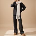 Yemelia charcoal knit lounge set with relaxed sweater and wide leg pants, featuring ribbed details and a cream fringed scarf.