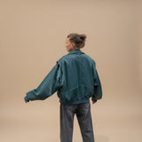 Yemelia dark teal faux leather bomber jacket with ribbed trim and contrast stitching. Zip front, relaxed fit.