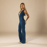 Yemelia deep V neck blue denim jumpsuit with flared legs and front zip closure.