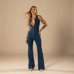 Yemelia deep V neck blue denim jumpsuit with flared legs and front zip closure.