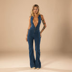 Yemelia deep V neck blue denim jumpsuit with flared legs and front zip closure.