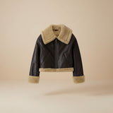 Yemelia dark brown faux leather jacket with cream shearling trim on collar, cuffs, and hem. Zip front closure.