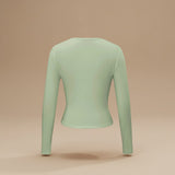 Yemelia light green long sleeve fitted crop top with thumbhole cuffs and a clean neckline, made from soft stretchy fabric.