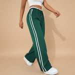 Yemelia high waist wide leg track pants in dark green with white side stripes and elastic waistband.