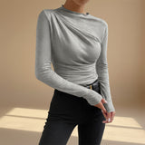 Yemelia grey long sleeve fitted top with asymmetrical neckline and ruched detailing, made from stretch fabric.