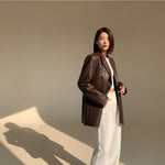 Yemelia oversized dark brown faux leather blazer with tailored structure, classic lapels, and functional pockets.