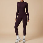 Yemelia plum purple long sleeve zip front sculpting one piece jumpsuit with a high neckline and full-length legs.