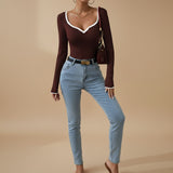 Yemelia dark brown ribbed long sleeve top with white contrast trim V-neck and cuffs, fitted silhouette.