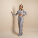 Yemelia silver sequin crop top with long sleeves and matching wide leg pants, featuring fringe detailing.