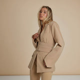 Yemelia tan belted tailored blazer with relaxed fit, featuring a self-tie belt and classic lapels. Made from smooth, structured fabric.