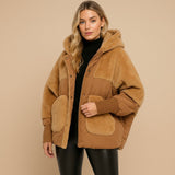 Yemelia oversized hooded puffer jacket in tan with textured finish, ribbed cuffs, and patch pockets. Cozy and stylish outerwear.