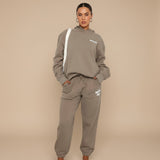 Yemelia taupe relaxed fit cotton blend hoodie and jogger set with graphic accent, elastic waistband, and drawstring.