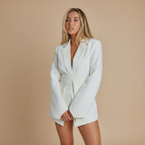 Yemelia white belted tailored blazer with relaxed fit, lapel neckline, and functional pockets. Smooth fabric.