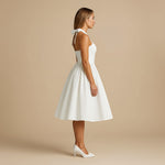 Yemelia white halter neck fit and flare midi dress with bow detail on back. Structured bodice and full skirt.