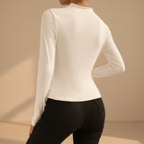 Yemelia white long sleeve fitted top with asymmetrical neckline and ruched detailing, made from stretch fabric.