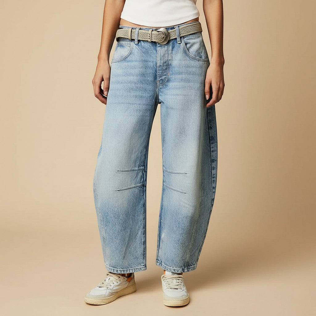 Yemelia light wash denim jeans with a relaxed fit, wide leg, and mid-rise waist. Features five-pocket styling and knee panel details.